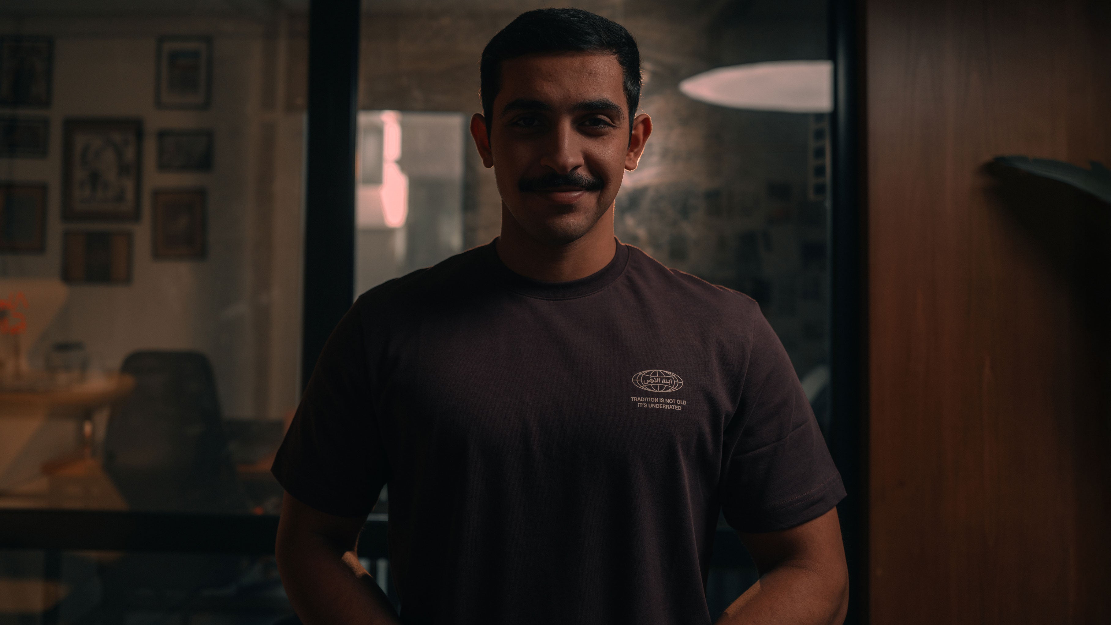 Man wearing a dark t-shirt with a logo in a dimly lit room